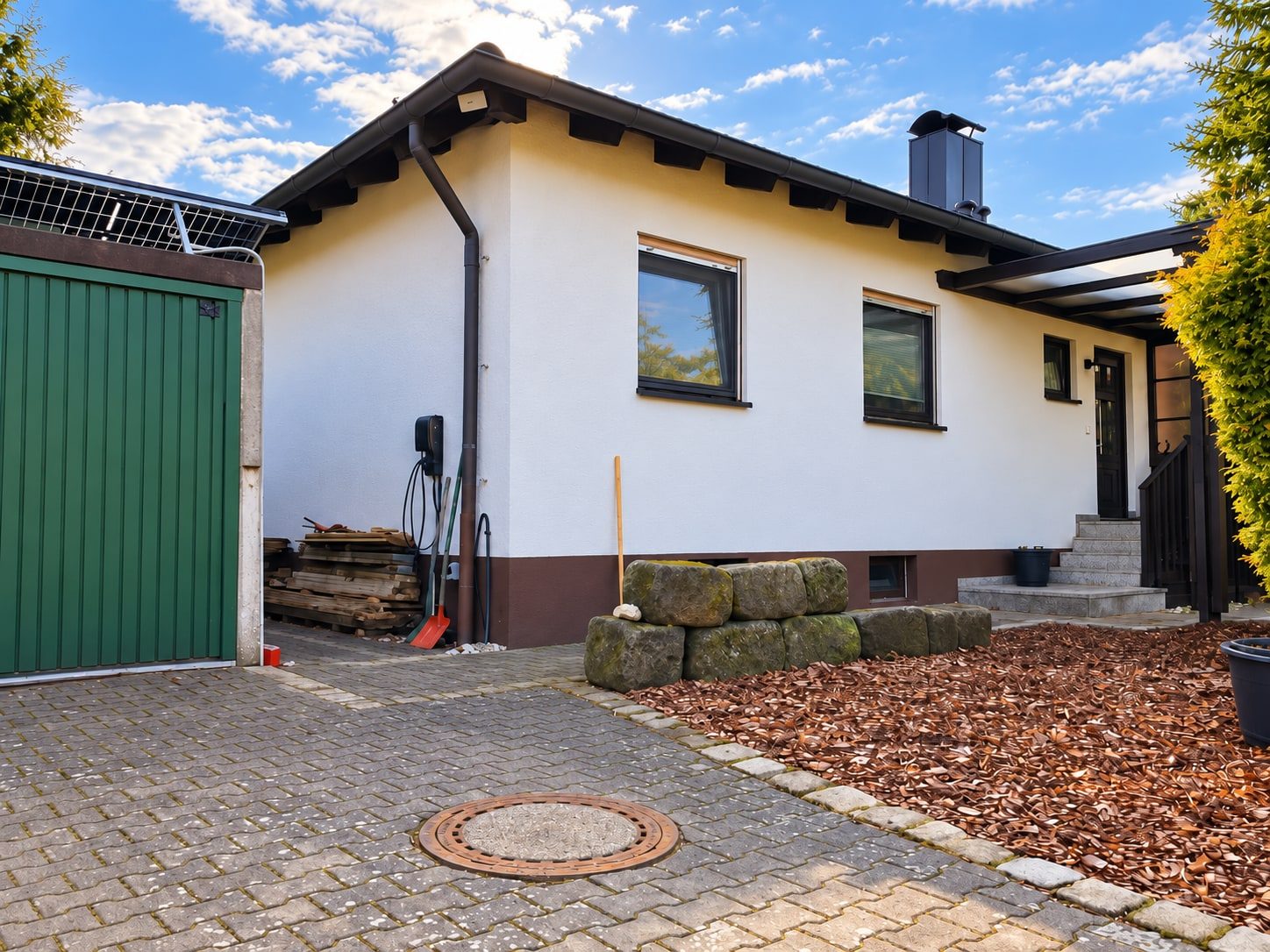 Hauseingang mit Treppe, Garage und Wallbox für Elektroautos